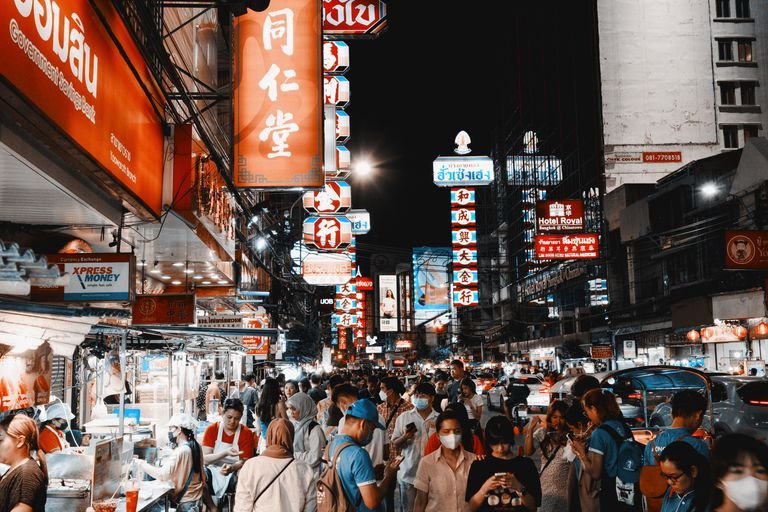 Vegan travel in Bangkok. Vibrant night life on a busy street in Bangkok's Chinatown filled with lights and crowds.