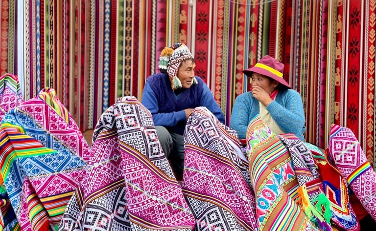 Vibrant Peruvian market showcasing traditional textiles with vendors engaging in conversation. Vegan travel south america